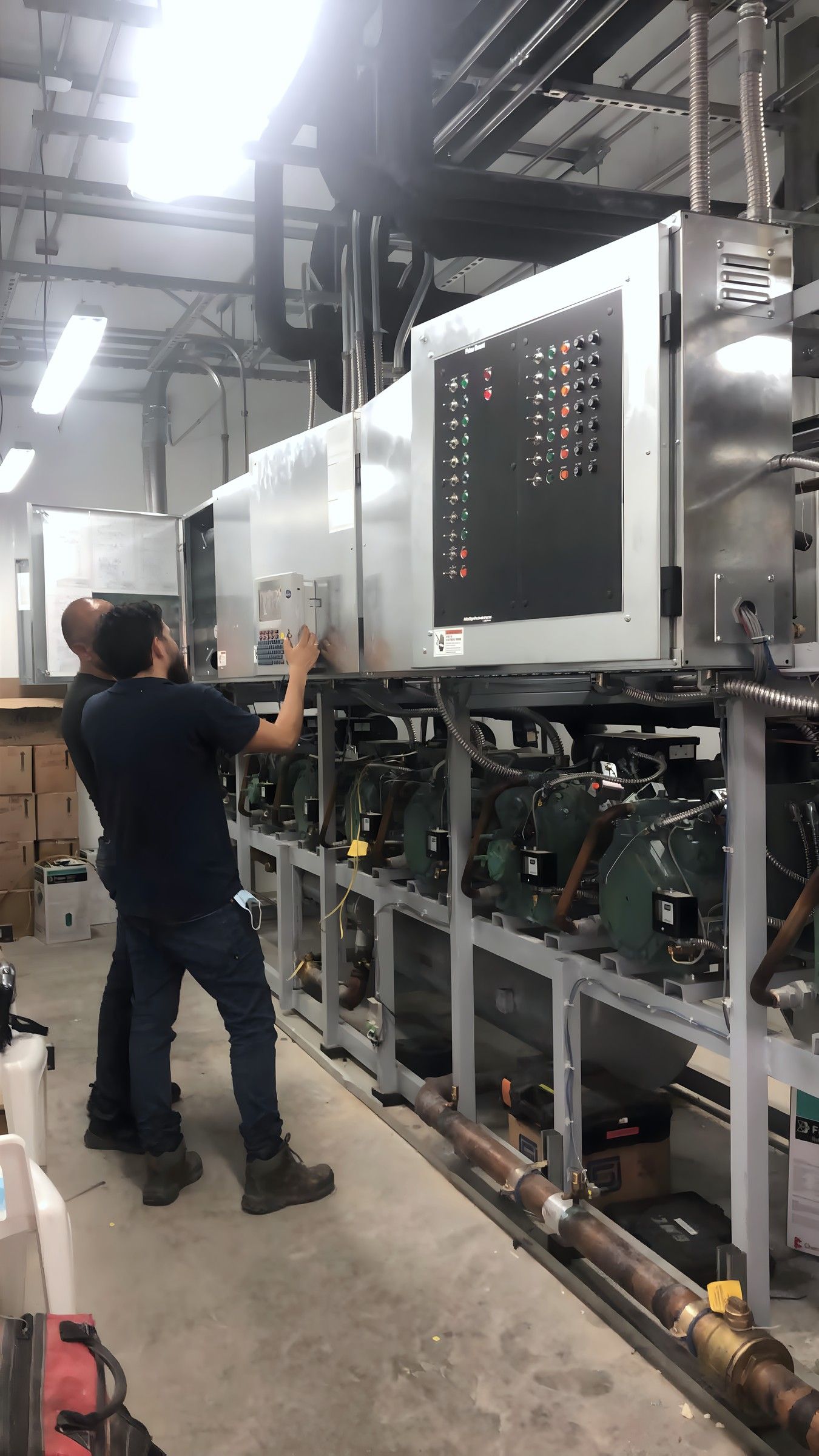 Técnico junto a un rack de compresores con su tablero de control